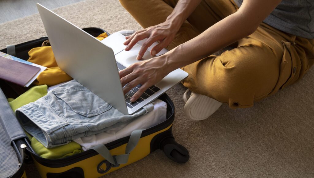 un nomade digitale che lavora con il portatile sopra la valigia