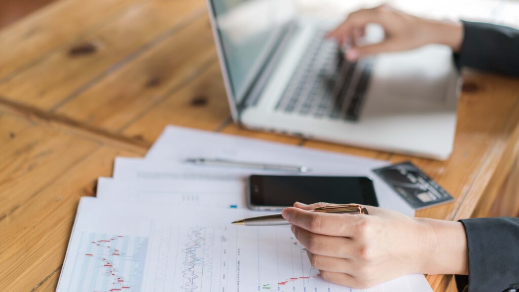 Donna al lavoro al computer con grafici finanziari e carta di credito sul tavolo